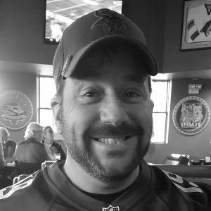 Close up of Danny Guckenburg at a sports bar wearing a ballcap and a football jersey