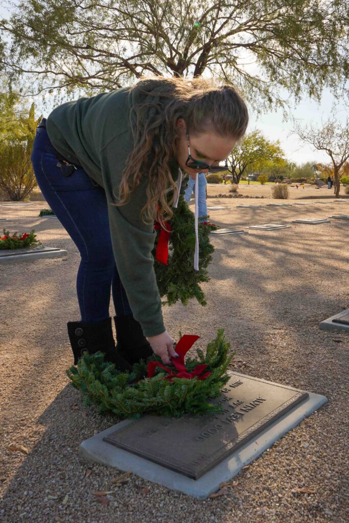 Havilah McMeans, Sonoran Desert Institute's Military and Veteran Services Representative, lays a wreath on a grave marker during Wreaths Across America's annual wreath laying at the National Memorial Cemetery of Arizona.