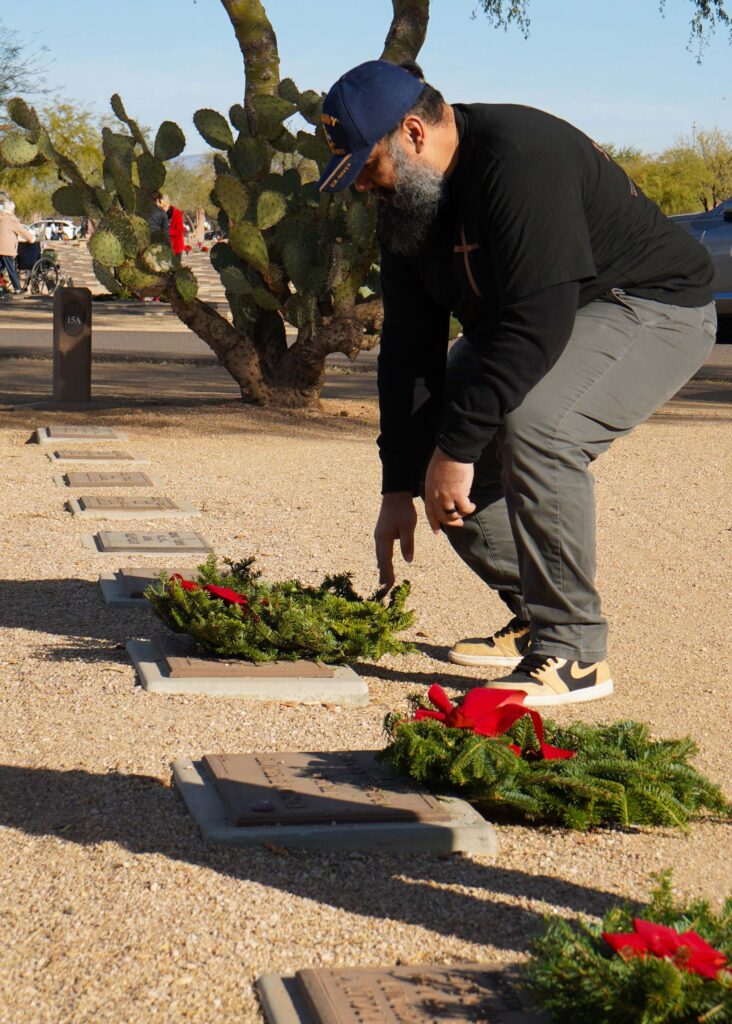 Arturo Adame, Sonoran Desert Institute's Financial Services Advisor, places a wreath to honor the fallen during Wreaths Across America's annual wreath laying at the National Memorial Cemetery of Arizona.