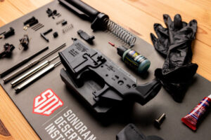 AR-15 lower receiver and gunsmithing tools laid out on an SDI work mat for the Modern Sporting Rifle course.