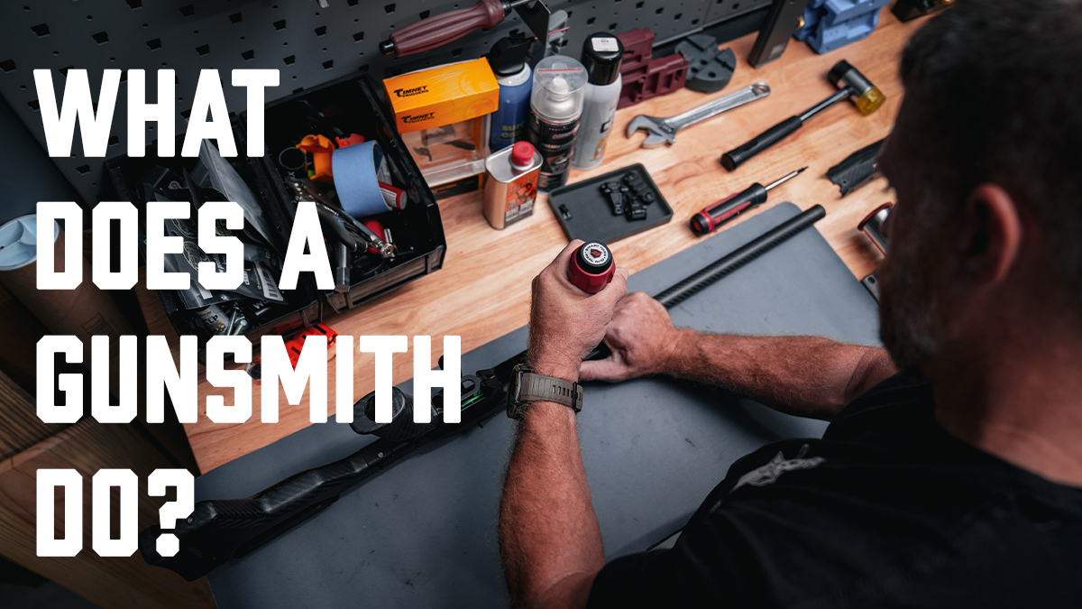 Gunsmith working at a workbench using tools to service a firearm